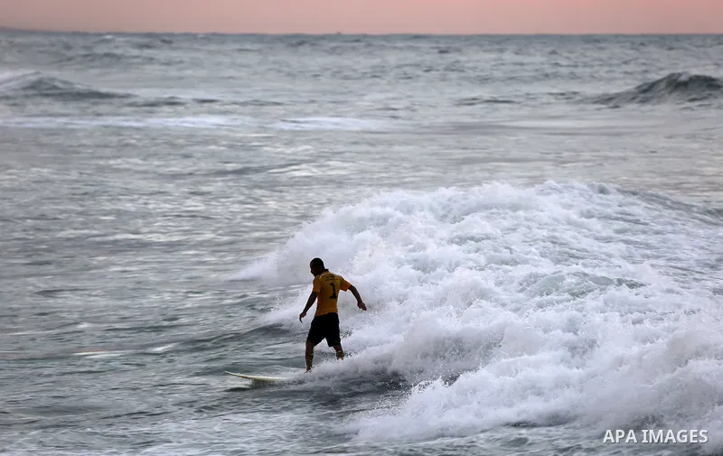 A Palestinian man surfs off the beach of Gaza City on November 2, 2016. Photo by Yasser Qudih