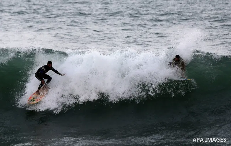 Palestinian men surf off the beach of Gaza City on November 2, 2016. Photo by Yasser Qudih