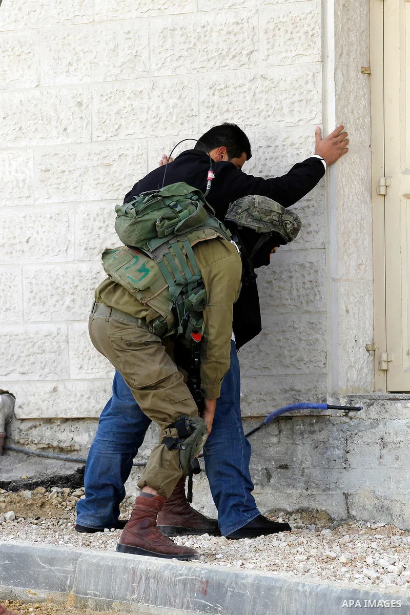 An Israeli soldier checks a Palestinian man at a checkpoint in the West Bank city of Hebron, on Nov. 04, 2016. Photo by Wisam Hashlamoun