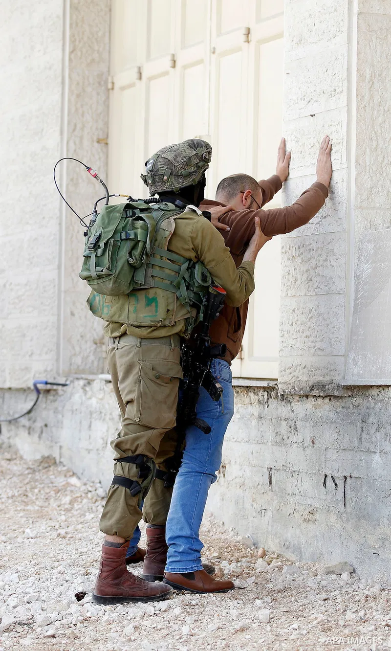 An Israeli soldier checks a Palestinian man at a checkpoint in the West Bank city of Hebron, on Nov. 04, 2016. Photo by Wisam Hashlamoun