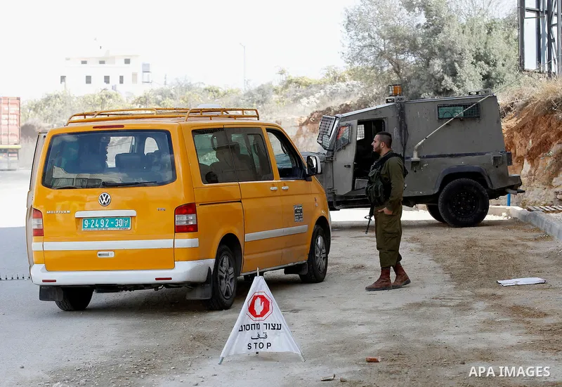An Israeli solider checks the ID of Palestinian drivers at a checkpoint in the West Bank city of Hebron, on Nov. 04, 2016. Photo by Wisam Hashlamoun