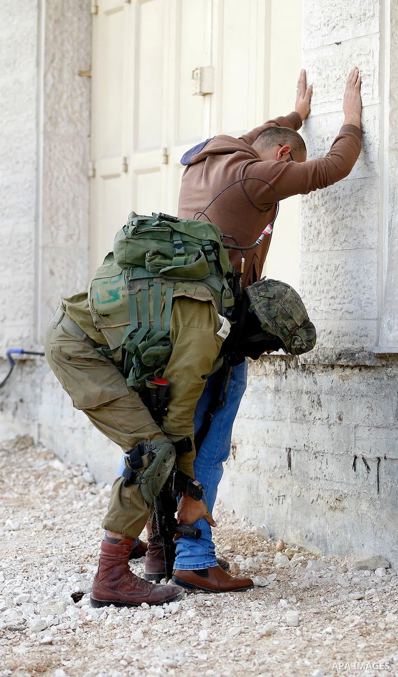 An Israeli soldier checks a Palestinian man at a checkpoint in the West Bank city of Hebron, on Nov. 04, 2016. Photo by Wisam Hashlamoun