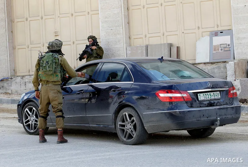 An Israeli solider checks the ID of Palestinian drivers at a checkpoint in the West Bank city of Hebron, on Nov. 04, 2016. Photo by Wisam Hashlamoun