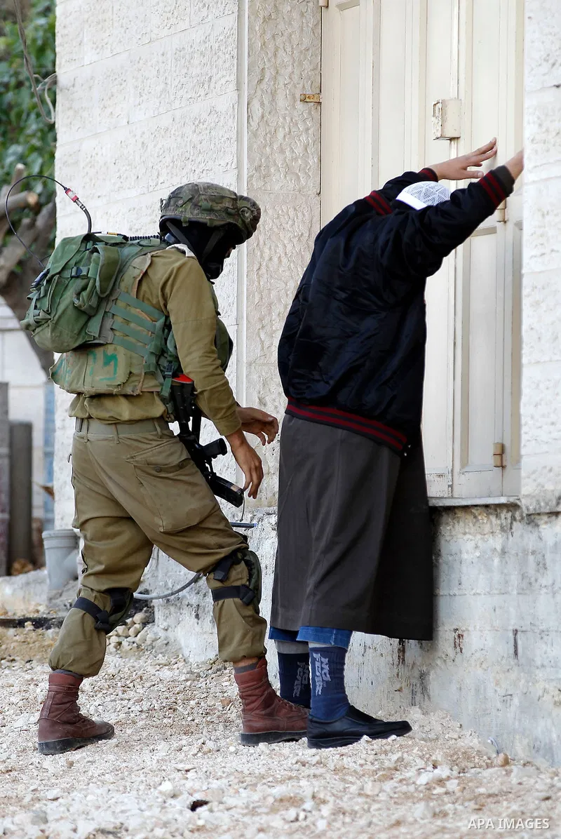 An Israeli soldier checks a Palestinian man at a checkpoint in the West Bank city of Hebron, on Nov. 04, 2016. Photo by Wisam Hashlamoun