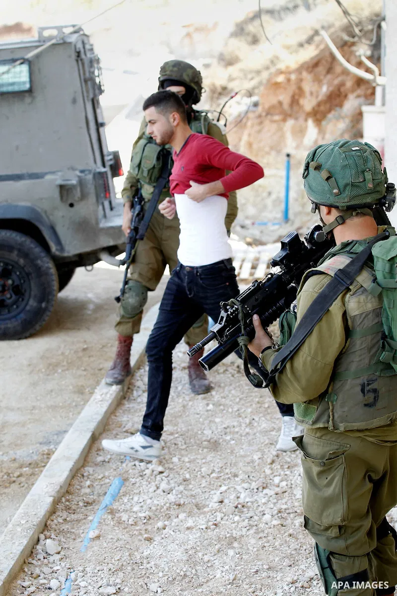 An Israeli soldier checks a Palestinian man at a checkpoint in the West Bank city of Hebron, on Nov. 04, 2016. Photo by Wisam Hashlamoun