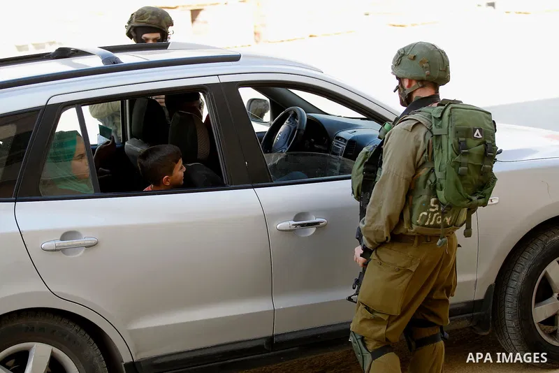 An Israeli solider checks the ID of Palestinian drivers at a checkpoint in the West Bank city of Hebron, on Nov. 04, 2016. Photo by Wisam Hashlamoun
