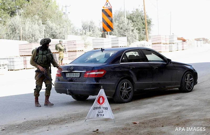 An Israeli solider checks the ID of Palestinian drivers at a checkpoint in the West Bank city of Hebron, on Nov. 04, 2016. Photo by Wisam Hashlamoun
