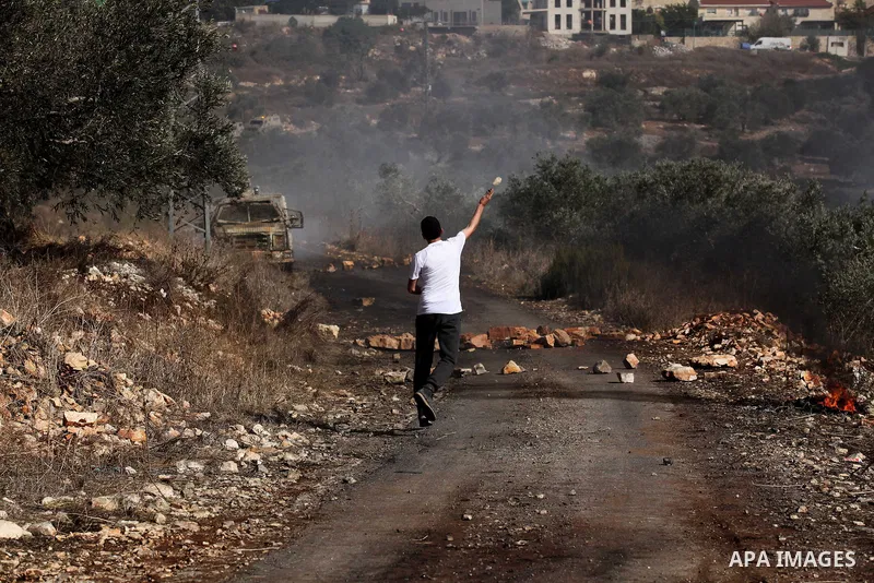 A Palestinian protester hurls stones towards Israeli security forces during clashes following a weekly demonstration against the expropriation of Palestinian land by Israel on Nov. 04, 2016, in the village of Kfar Qaddum...