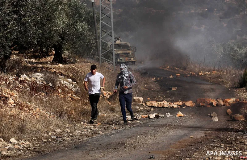 Palestinian protesters run for cover during clashes with Israeli security forces following a weekly demonstration against the expropriation of Palestinian land by Israel on Nov. 04, 2016, in the village of Kfar Qaddum, n...