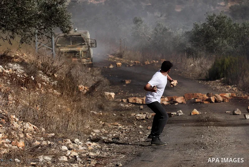 A Palestinian protester hurls stones towards Israeli security forces during clashes following a weekly demonstration against the expropriation of Palestinian land by Israel on Nov. 04, 2016, in the village of Kfar Qaddum...