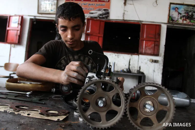 A Palestinian boy works at a mechanic shop in Rafah in the southern Gaza strip, on November 7, 2016. Photo by Abed Rahim Khatib