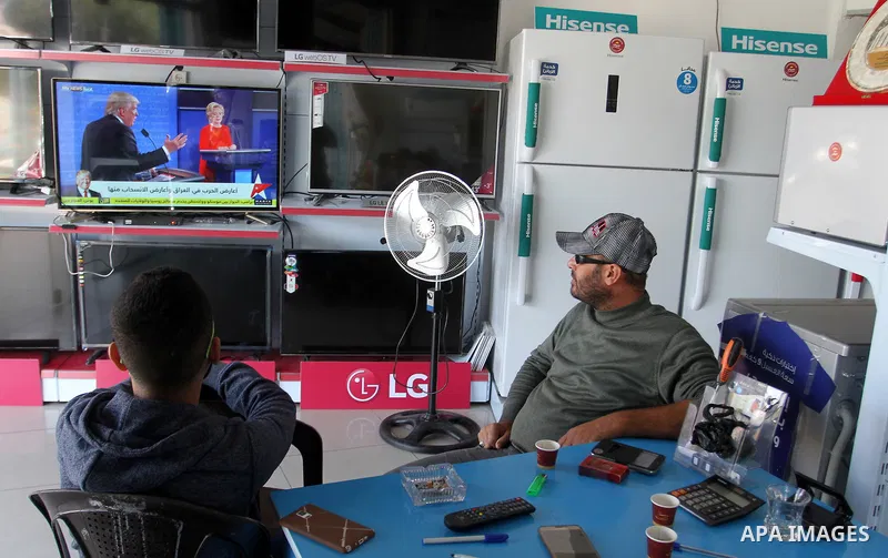 Palestinian men watch broadcasting of the 2016 U.S. presidential election results on TV in Rahaf in the southern Gaza strip, on November 9, 2016. U.S. Republican Donald Trump has been elected the 45th president of the Un...