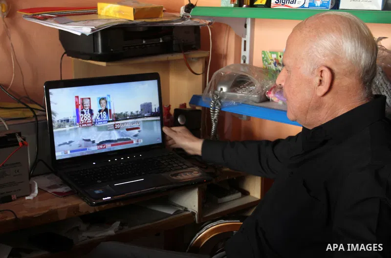A Palestinian man watches broadcasting of the 2016 U.S. presidential election results on TV in Rahaf in the southern Gaza strip, on November 9, 2016. Republican Donald Trump has been elected the 45th president of the Uni...