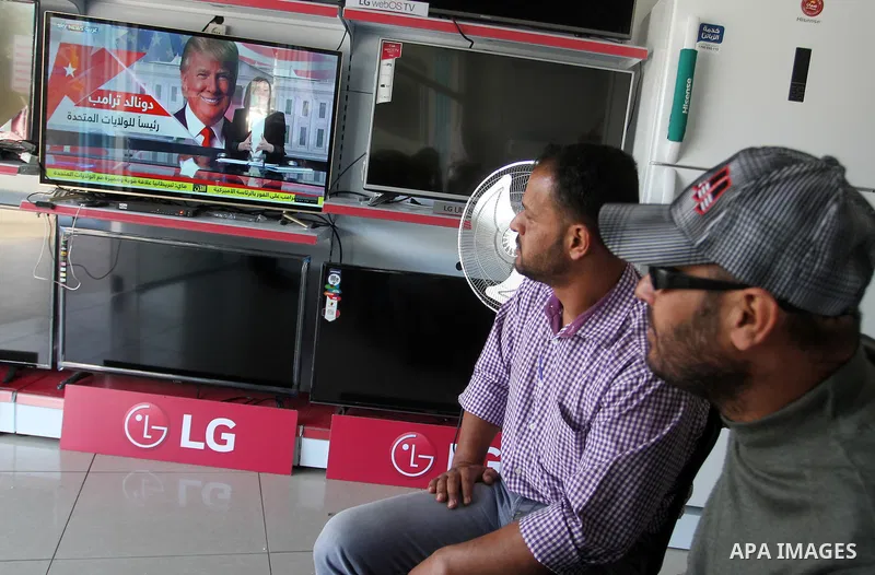 Palestinian men watch broadcasting of the 2016 U.S. presidential election results on TV in Rahaf in the southern Gaza strip, on November 9, 2016. U.S. Republican Donald Trump has been elected the 45th president of the Un...