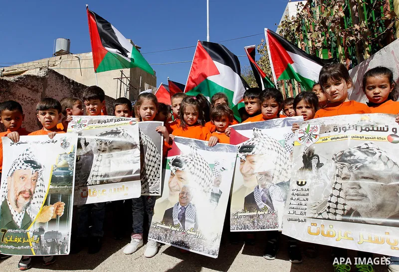 Palestinian children hold posters of the late Palestinian leader Yasser Arafat to mark the 12 anniversary of his death in the West Bank city of Hebron, 10 November 2016. Photo by Wisam Hashlamoun