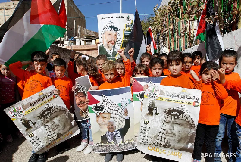 Palestinian school boys hold posters of the late Palestinian leader Yasser Arafat to mark the 12 anniversary of his death in the West Bank city of Hebron, 10 November 2016. Photo by Wisam Hashlamoun