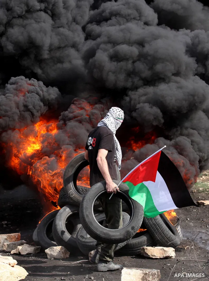 A Palestinian protester throws a tire on a fire during clashes with Israeli security forces following a demonstration against the expropriation of Palestinian land by Israel on November 11, 2016 in the village of Kfar Qa...