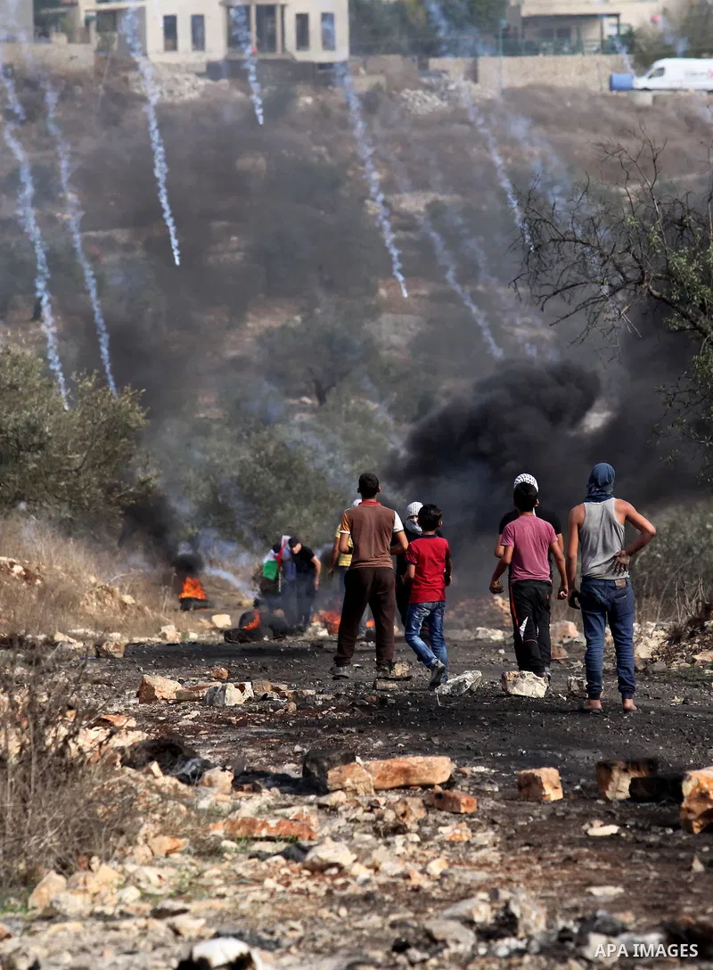 Palestinian protesters run for cover from tear gas canister fired by Israeli security forces during clashes following a demonstration against the expropriation of Palestinian land by Israel on November 11, 2016 in the vi...