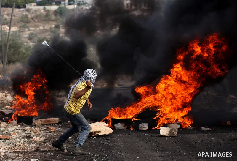 A Palestinian protester uses a slingshot to hurl stones towards Israeli security forces during clashes following a demonstration against the expropriation of Palestinian land by Israel on November 11, 2016 in the village...