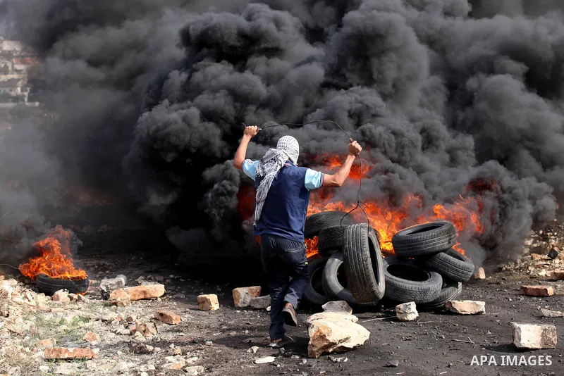 A Palestinian protester throws a tire on a fire during clashes with Israeli security forces following a demonstration against the expropriation of Palestinian land by Israel on November 11, 2016 in the village of Kfar Qa...