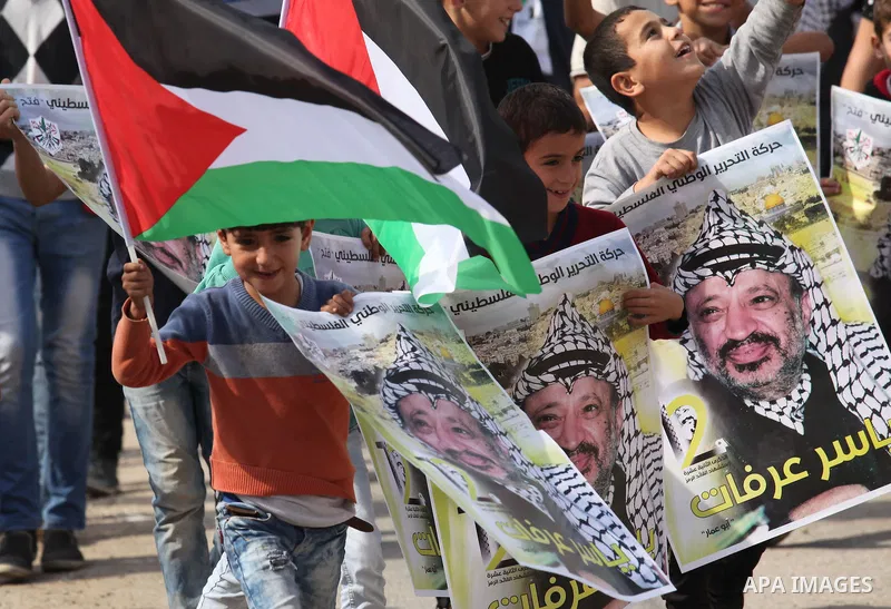 Palestinian protesters wave the national flag and carry posters of Palestinian leader Yasser Arafat, during a demonstration to mark the 12th anniversary of the former leader's death, on November 11, 2016 in the village o...