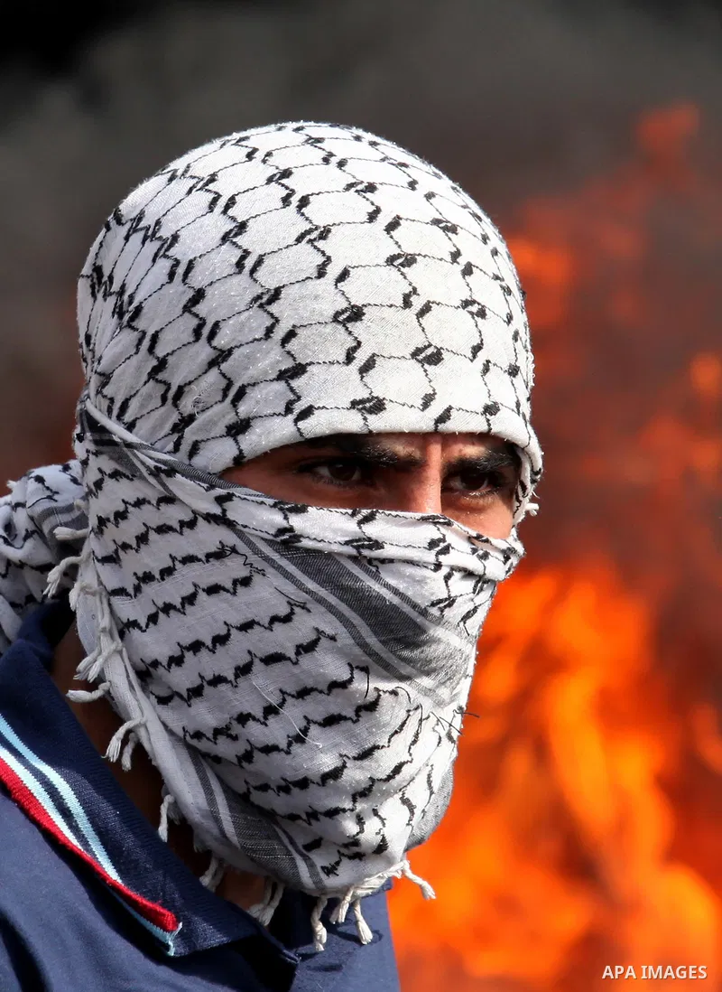 A Palestinian protester stands in front of burning tires during clashes with Israeli security forces following a demonstration against the expropriation of Palestinian land by Israel on November 11, 2016 in the village o...