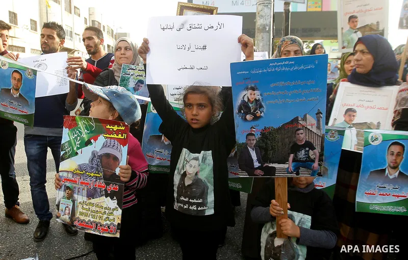 Palestinians hold banners during a protest demanding Israel return the bodies of Palestinians who allegedly stabbed Israelis, in the West Bank city of Hebron, on Nov. 13, 2016. Photo by Wisam Hashlamoun