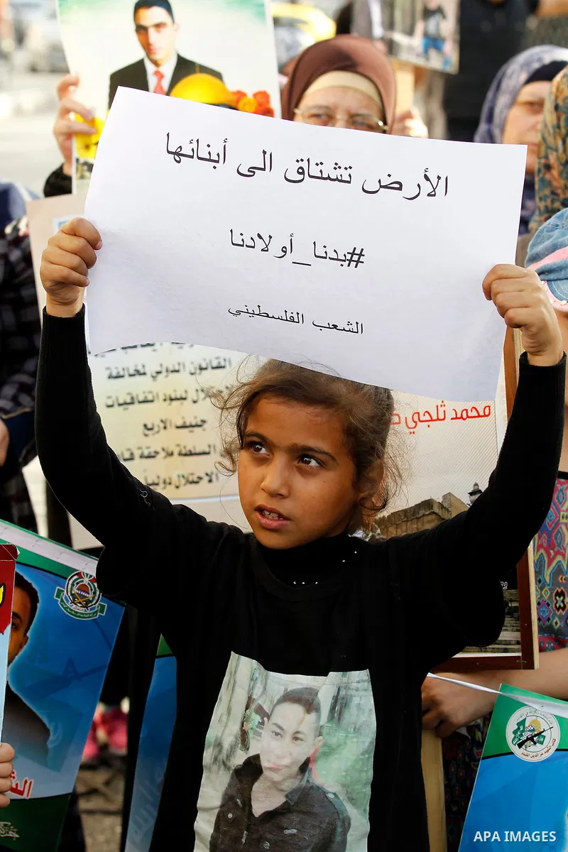 Palestinians hold banners during a protest demanding Israel return the bodies of Palestinians who allegedly stabbed Israelis, in the West Bank city of Hebron, on Nov. 13, 2016. Photo by Wisam Hashlamoun