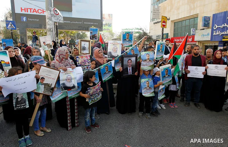 Palestinians hold banners during a protest demanding Israel return the bodies of Palestinians who allegedly stabbed Israelis, in the West Bank city of Hebron, on Nov. 13, 2016. Photo by Wisam Hashlamoun
