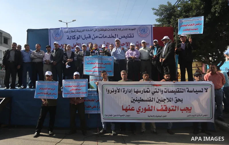 Palestinians hold banners during a protest against the UNRWA decision to reduce of the aid in front of the headquarters United Nations Relief and Works Agency (UNRWA), in Gaza city, on Nov. 14, 2016. Photo by Mohammed As...