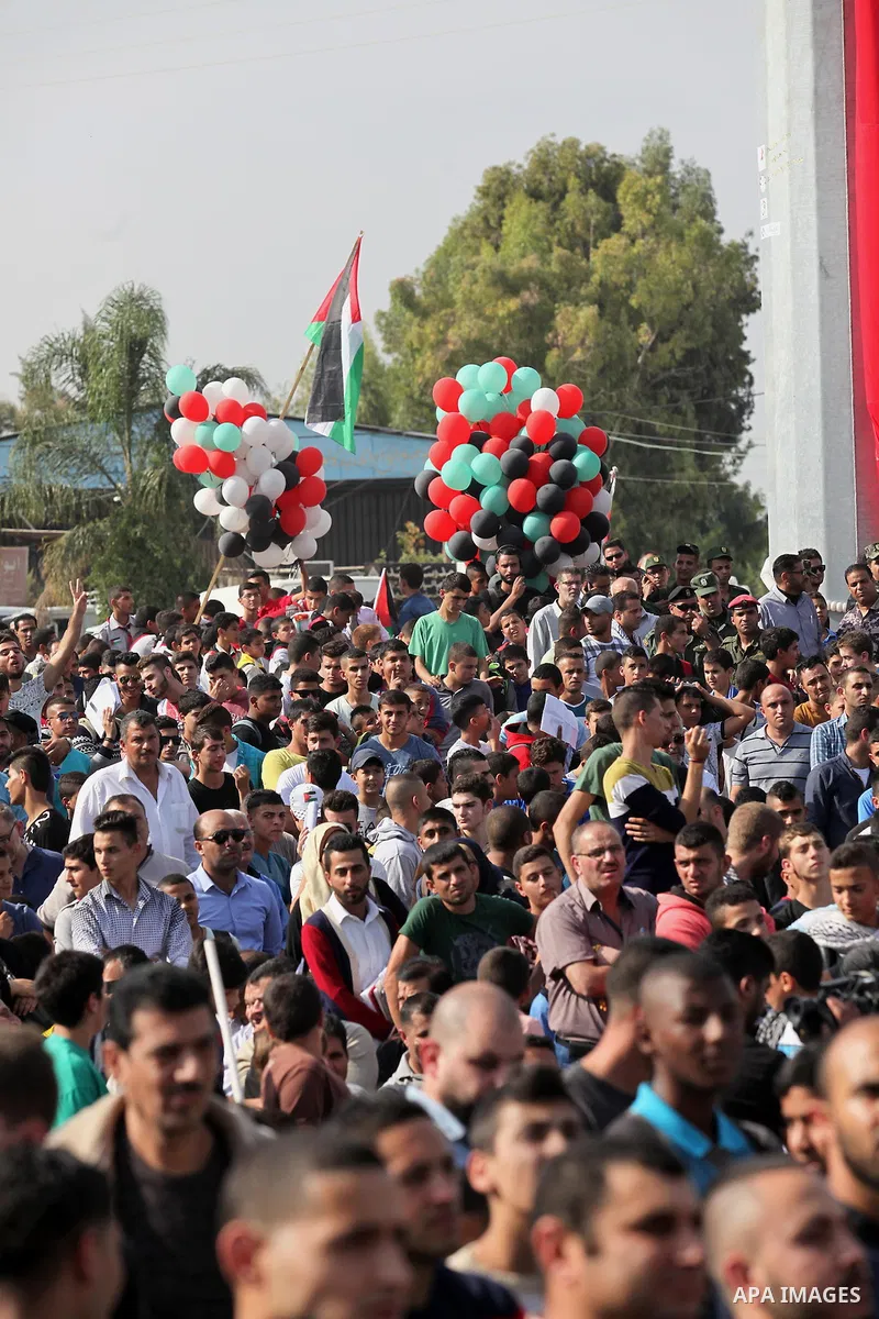 Palestinians watch the raising of a Palestinian flag during a rally marking the Palestinian Declaration of Independence in 1988, in the West Bank city of Tulkarm November 14, 2016. Photo by Nedal Eshtayah