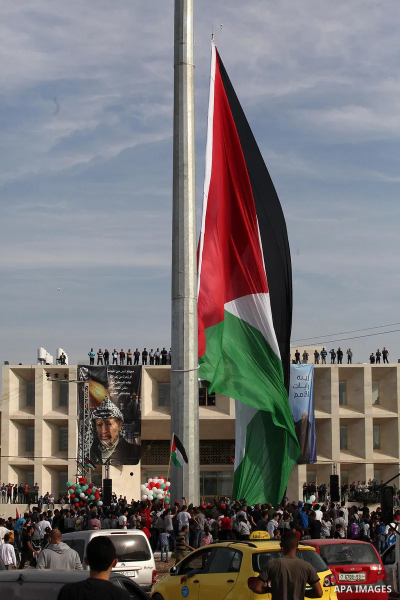 Palestinians watch the raising of a Palestinian flag during a rally marking the Palestinian Declaration of Independence in 1988, in the West Bank city of Tulkarm November 14, 2016. Photo by Nedal Eshtayah