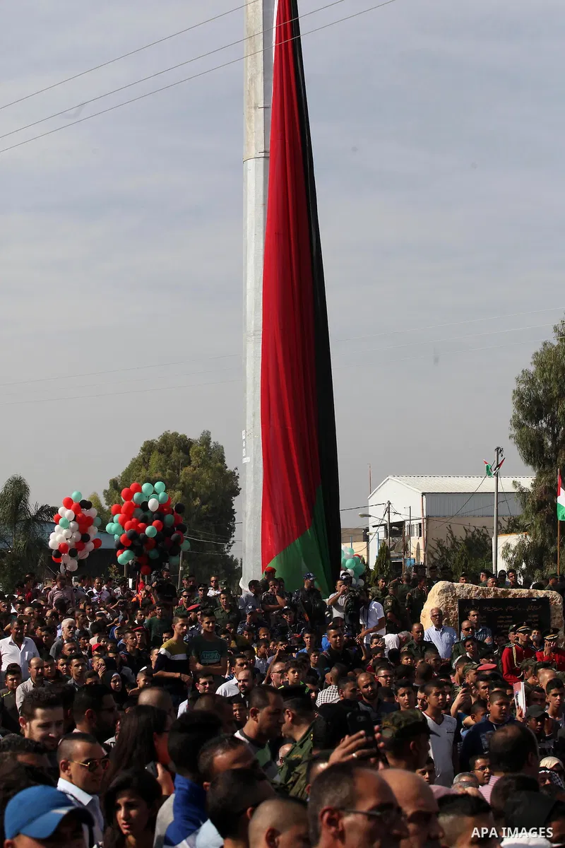 Palestinians watch the raising of a Palestinian flag during a rally marking the Palestinian Declaration of Independence in 1988, in the West Bank city of Tulkarm November 14, 2016. Photo by Nedal Eshtayah
