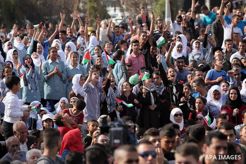Palestinians watch the raising of a Palestinian flag during a rally marking the Palestinian Declaration of Independence in 1988, in the West Bank city of Tulkarm November 14, 2016. Photo by Nedal Eshtayah