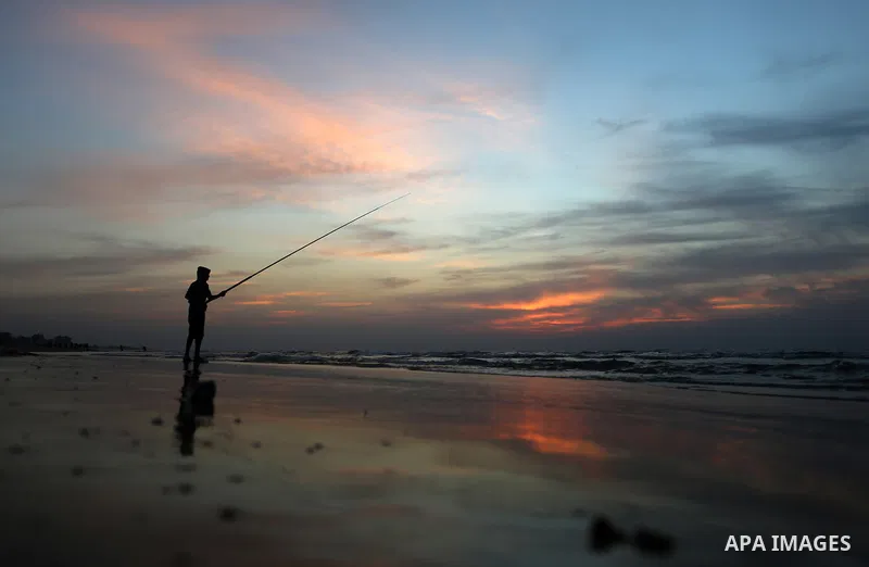 A Palestinian man uses a hook to fishing off the beach of Gaza City on November 14, 2016. Photo by Yasser Qudih