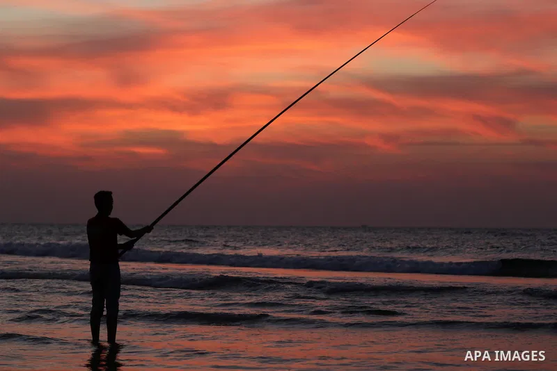 A Palestinian man uses a hook to fishing off the beach of Gaza City on November 14, 2016. Photo by Yasser Qudih
