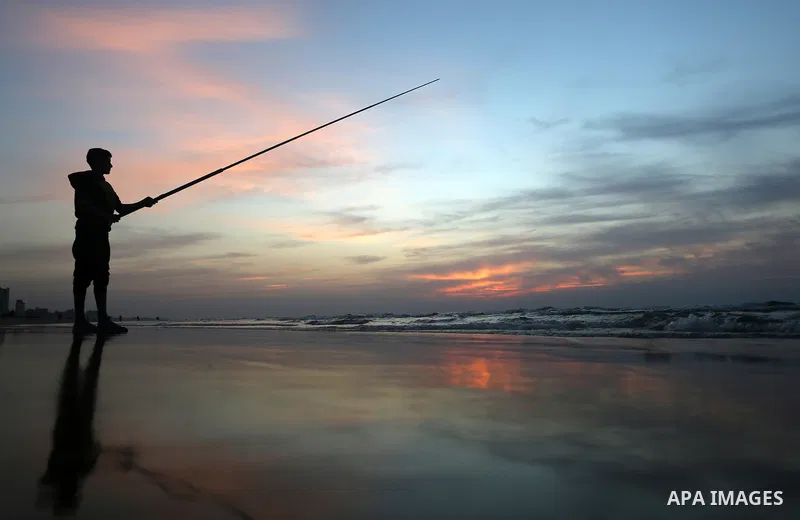 A Palestinian man uses a hook to fishing off the beach of Gaza City on November 14, 2016. Photo by Yasser Qudih
