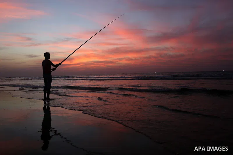 A Palestinian man uses a hook to fishing off the beach of Gaza City on November 14, 2016. Photo by Yasser Qudih