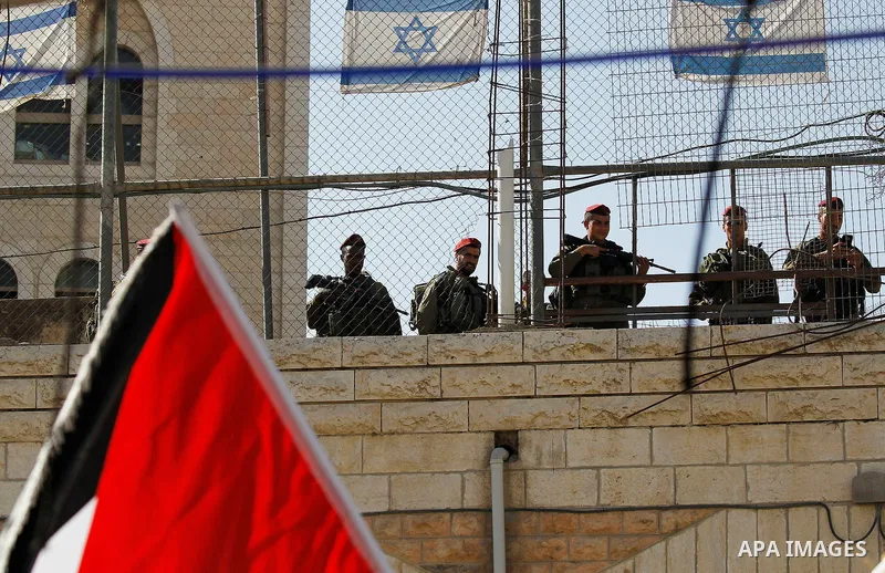 Israeli soldiers watch Palestinians (unseen) taking part in a march marking the Palestinian national day of independence, in the West Bank city of Hebron on November 15, 2016. Photo by Wisam Hashlamoun
