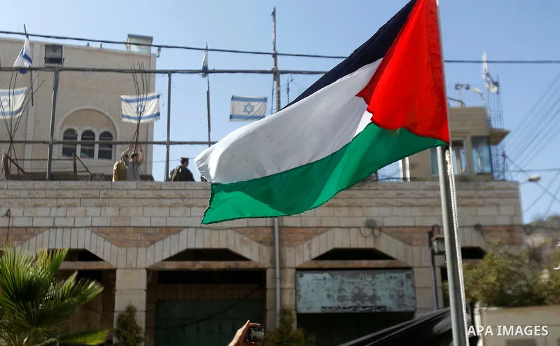 A Palestinian national flag is seen flying past Israeli soldiers (top) during a march marking the Palestinian national day of independence in the West Bank city of Hebron on November 15, 2016. Photo by Wisam Hashlamoun