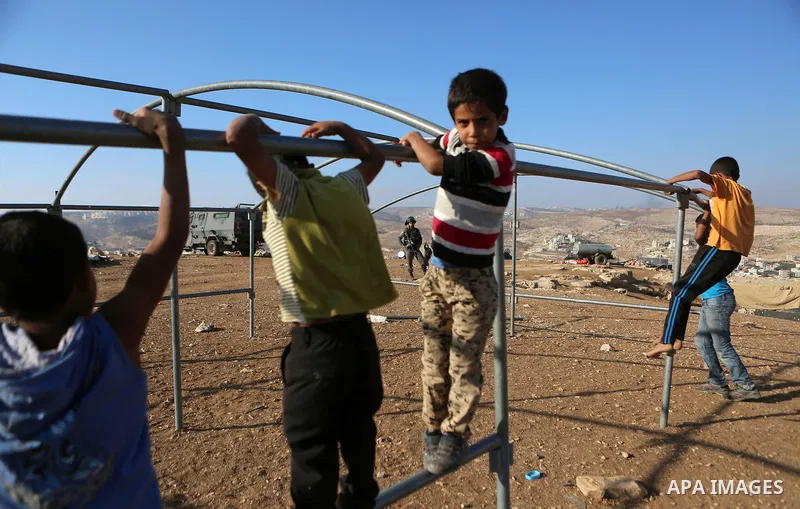 Palestinian Bedouin children play as Israeli security forces confiscate barracks in the Bedouin residential area after Israeli authorities said it was built without a permit in the West Bank village of Jab'a, north east...