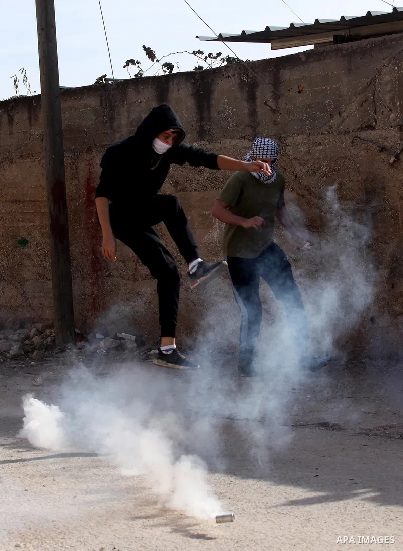 A Palestinian protester kicks back a tear gas canister fired by Israeli security forces during clashes following a demonstration against the expropriation of Palestinian land by Israel on November 18, 2016 in the village...