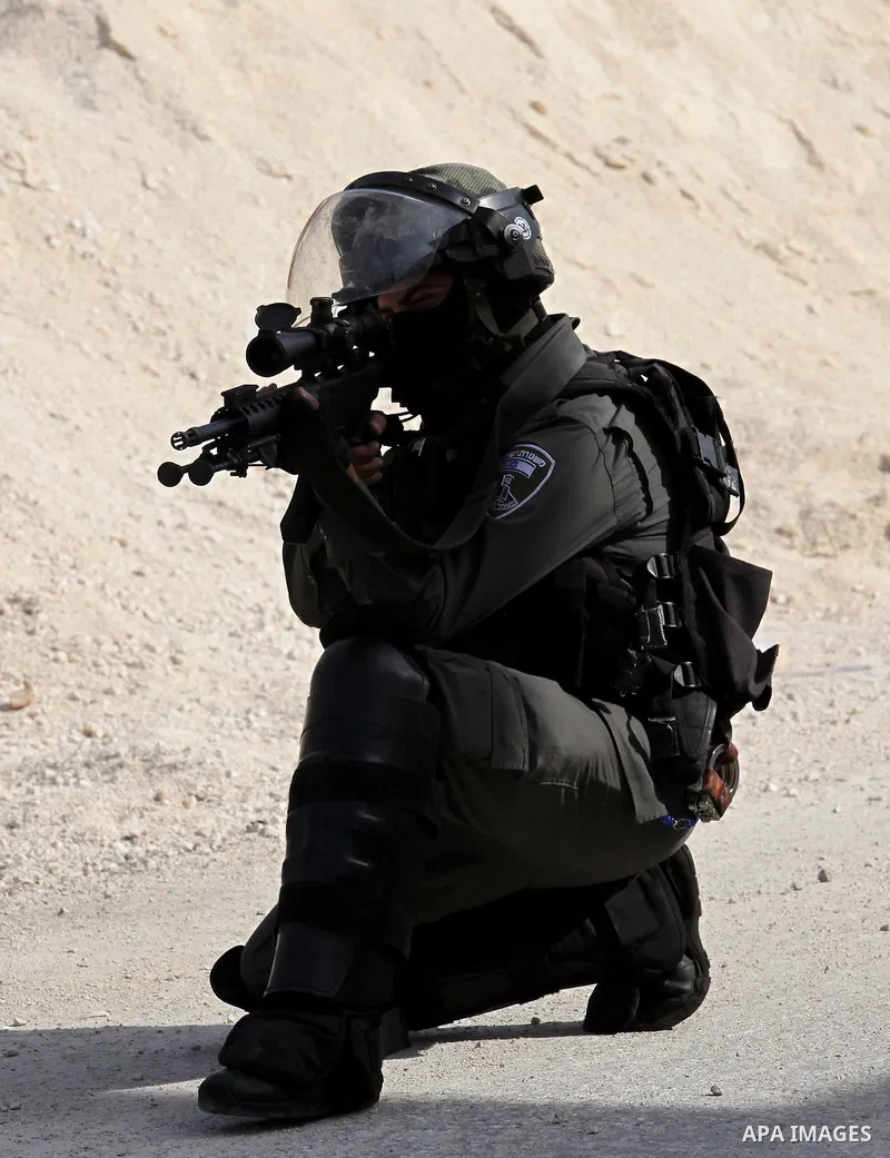 An Israeli border policeman aims his weapon at Palestinian protesters during clashes following a demonstration against the expropriation of Palestinian land by Israel on November 18, 2016 in the village of Kfar Qaddum, n...