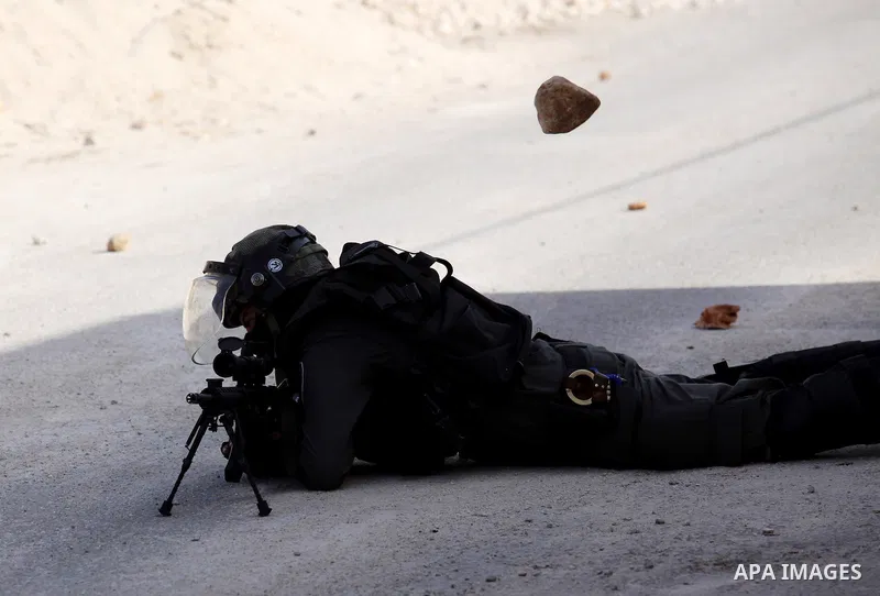 An Israeli border policeman aims his weapon at Palestinian protesters during clashes following a demonstration against the expropriation of Palestinian land by Israel on November 18, 2016 in the village of Kfar Qaddum, n...