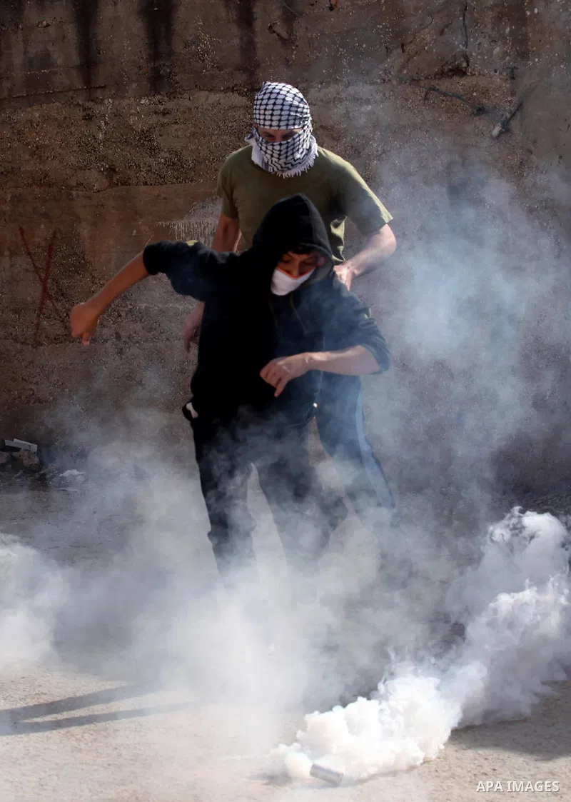 A Palestinian protester kicks back a tear gas canister fired by Israeli security forces during clashes following a demonstration against the expropriation of Palestinian land by Israel on November 18, 2016 in the village...