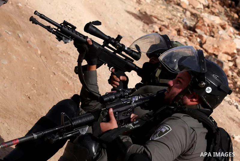An Israeli border policeman aims his weapon at Palestinian protesters during clashes following a demonstration against the expropriation of Palestinian land by Israel on November 18, 2016 in the village of Kfar Qaddum, n...