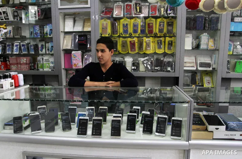 A Palestinian man work at his mobile phone shop in Rafah in the southern Gaza strip, on November 20, 2016. Interior Ministry in Gaza are trying to stop the sale and distribution of pre-paid SIM cards from Israeli cellula...