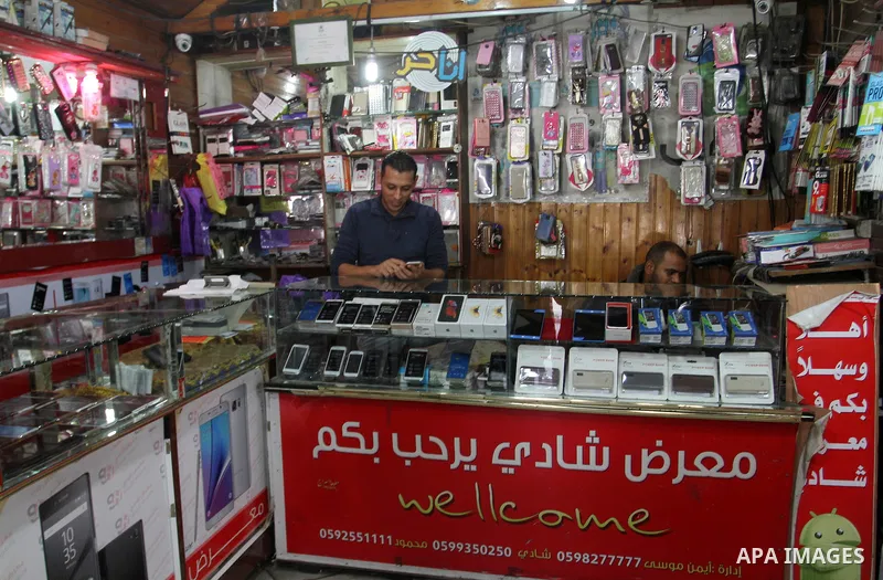 A Palestinian man work at his mobile phone shop in Rafah in the southern Gaza strip, on November 20, 2016. Interior Ministry in Gaza are trying to stop the sale and distribution of pre-paid SIM cards from Israeli cellula...