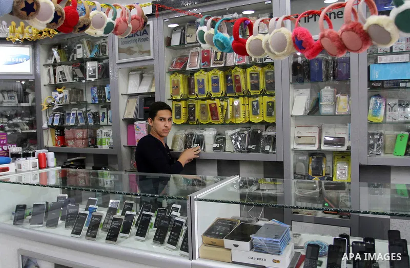 A Palestinian man work at his mobile phone shop in Rafah in the southern Gaza strip, on November 20, 2016. Interior Ministry in Gaza are trying to stop the sale and distribution of pre-paid SIM cards from Israeli cellula...