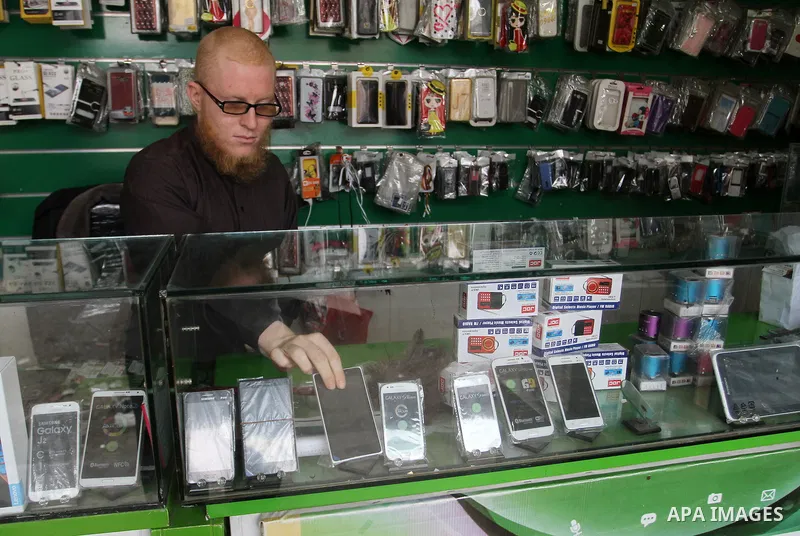A Palestinian man work at his mobile phone shop in Rafah in the southern Gaza strip, on November 20, 2016. Interior Ministry in Gaza are trying to stop the sale and distribution of pre-paid SIM cards from Israeli cellula...
